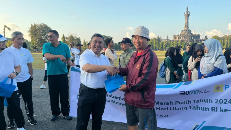 Plh General manager PT PLN (Persero) UID Bali Rizky Mochamad memberikan bendera kepada salah satu warga.