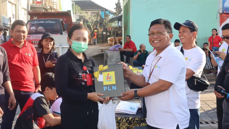 Manager PT PLN (Persero) Unit Pelaksana Pelayanan Pelanggan (UP3) Bali Timur Agung Prabowo (kaos putih) memberikan souvenir kepada salah satu karyawan Rumah Sakit Umum Daerah RSUD Bangli yang sudah mendownload aplikasi PLN Mobile dan sudah ada history transaksinya.