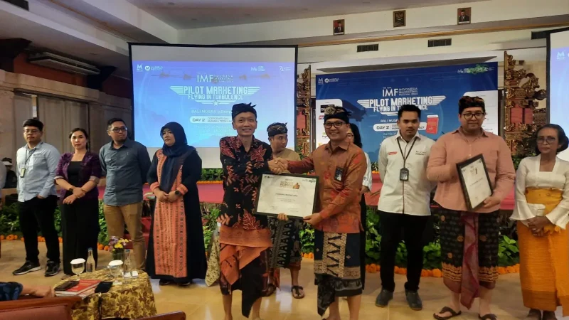 Pihak Markplus Institute (kiri) memberi penghargaan kepada salah satu tenaga pemasar PLN, I Komang Rentadi Arta (kanan) sebagai Service Person of The Year Bali Nusra 2024.