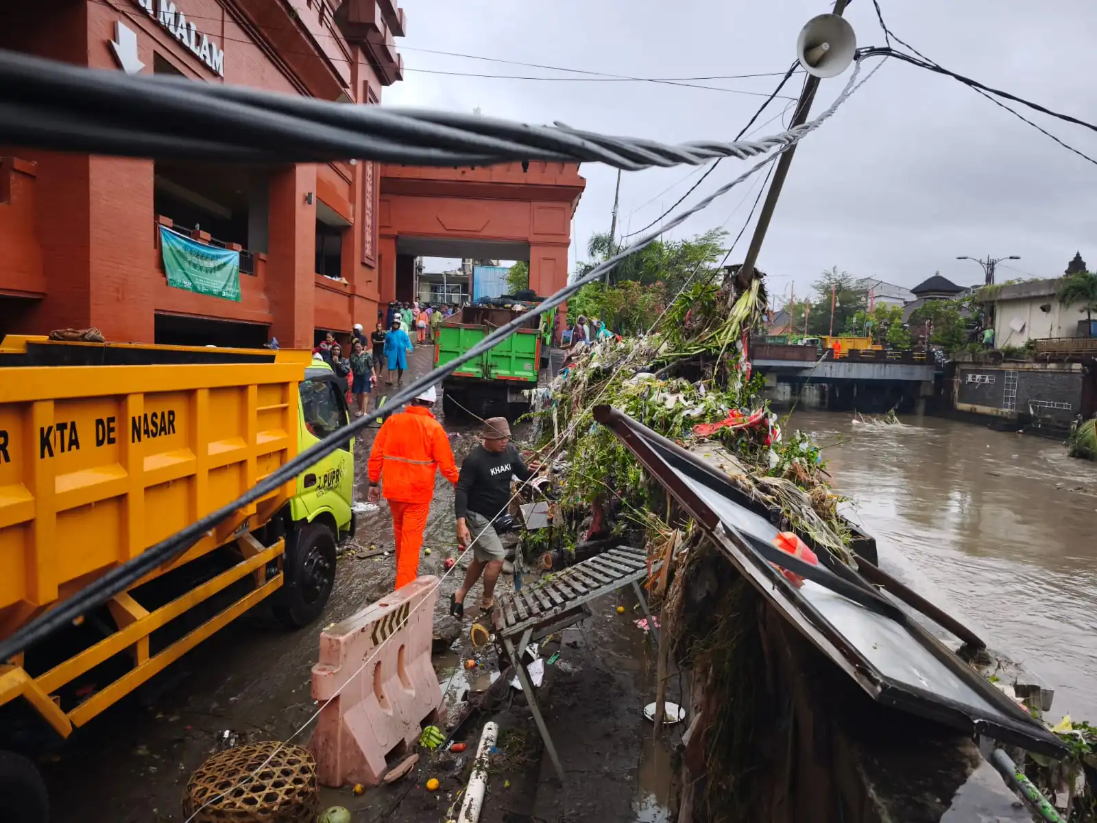Petugas PLN berjibaku lakukan penanganan tiang listrik roboh tergerus longsor akibat cuaca hujan di pasar Kumbasari Denpasar.